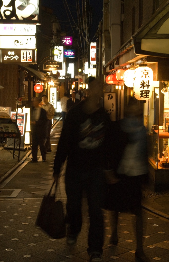 A young couple comes out of a popular street at night