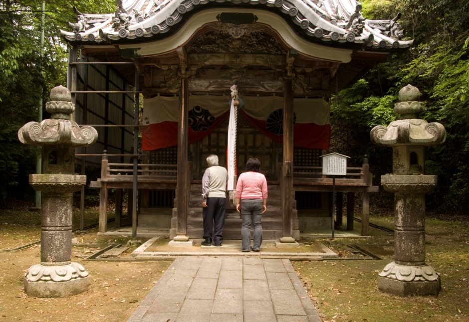 An elderly couple offer prayers and bow at a Shinto shrine